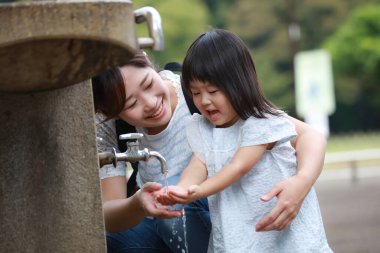 Küçük kızıyla birlikte parkta Asyalı bir kız.