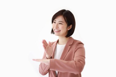 Asyalı genç bir iş kadını, izole bir arka planda el kol hareketi yapıyor. 