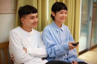 Genç Asyalı çift televizyon izliyor.