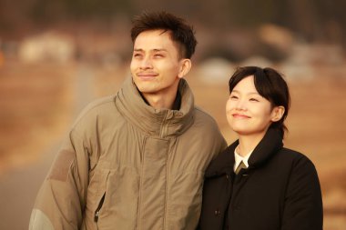 Dışarıda poz veren iki Asyalı genç çiftin portresi.