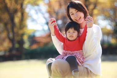 Küçük tatlı Asyalı kız ve annesi parkta eğleniyor. 