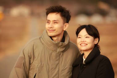 Dışarıda poz veren iki Asyalı genç çiftin portresi.