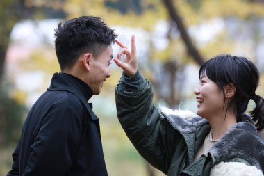 Genç bir çift parkta el kol geziyor.