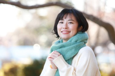 Açık havada poz veren gülümseyen Asyalı bir kadının portresi.