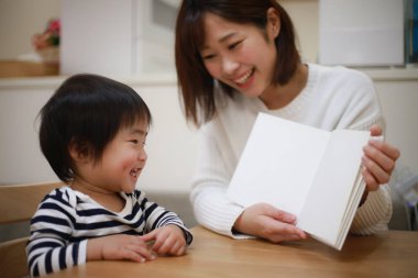 Mutlu Asyalı aile evde kitap okuyor. 