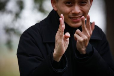 Genç Asyalı adam el kol hareketi yapıyor.