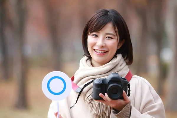 asian woman holding camera and tag