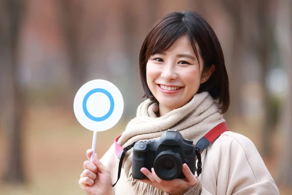 asian woman holding camera and tag