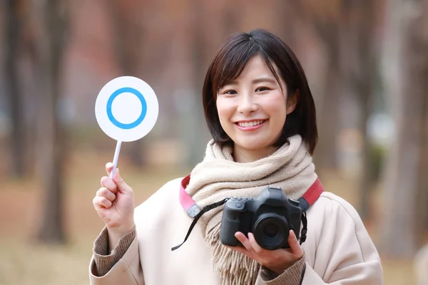 asian woman holding camera and tag