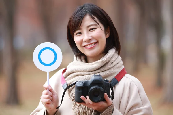 asian woman holding camera and tag