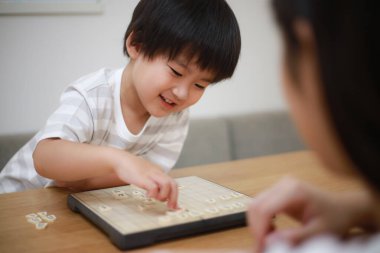 Asyalı küçük çocuk annesiyle oynuyor.