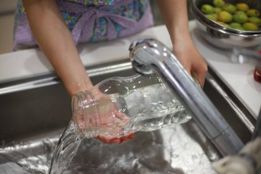 Kadın mutfakta bulaşık yıkıyor. 