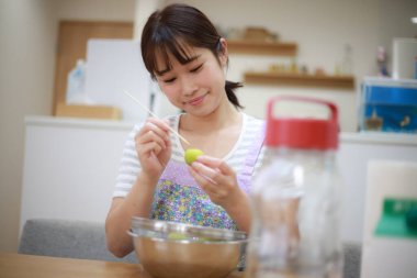 Genç Asyalı kadın mutfakta konserve konserveler için kayısı hazırla.