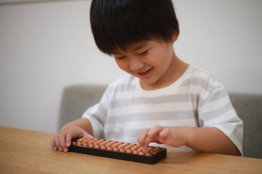 Küçük çocuk evde abaküsle oynuyor.