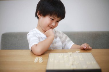 Küçük tatlı Asyalı çocuk evde eğitim oyunu oynuyor.