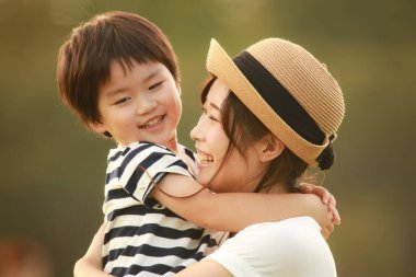 Mutlu anne ve oğul çimenlerde oynuyorlar.