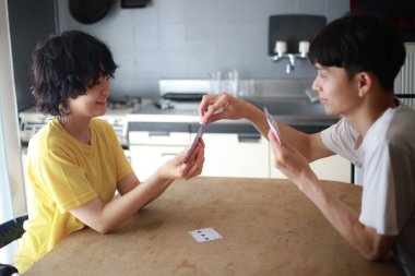 Mutlu Asyalı çift evde kağıt oynuyor.