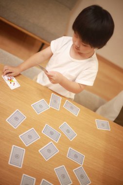 İskambil oynayan Asyalı küçük çocuk. 