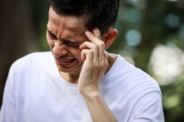 Baş ağrısı olan Asyalı genç bir adam. 