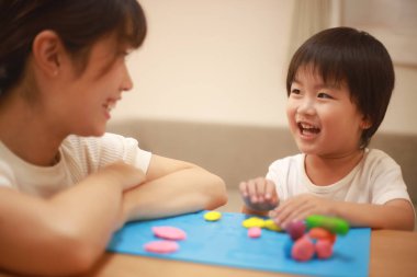 Anne ve oğlu çamurla oynuyor.