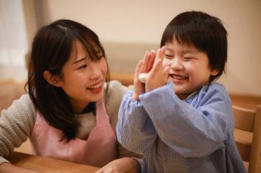 Küçük çocuk ve annesi mangırla oynuyorlar. 