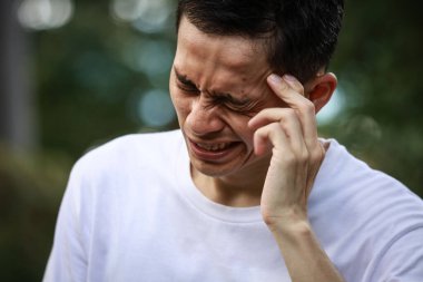 Baş ağrısı olan Asyalı genç bir adam. 