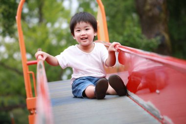 Sevimli çocuk dışarıda oyun alanında eğleniyor.