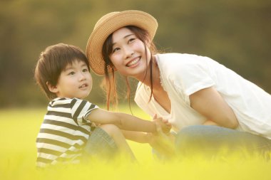 Mutlu anne ve oğul çimenlerde oynuyorlar.