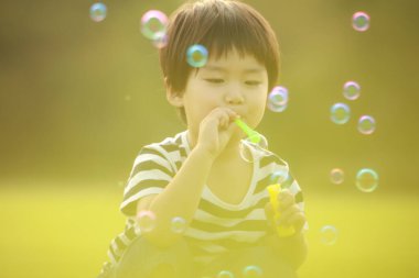 Parkta sabun köpükleri olan Asyalı küçük çocuk. 