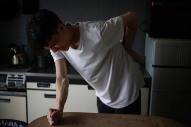 Sırtında acı hisseden Asyalı bir adam.