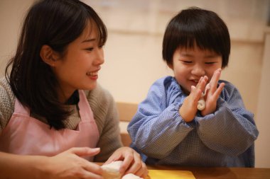 Küçük çocuk ve annesi mangırla oynuyorlar. 