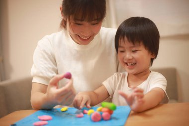 Anne ve oğlu çamurla oynuyor.