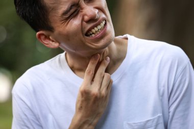 Boğazı ağrıyan Asyalı bir adamın yakın çekimi. 