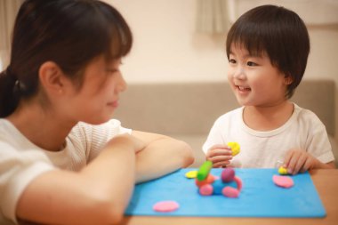 Anne ve oğlu çamurla oynuyor.