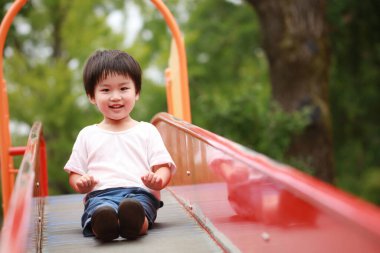 Asyalı çocuk oyun alanında kayıyor