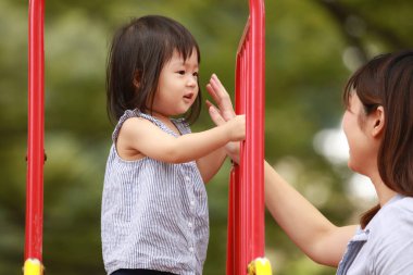 Asyalı mutlu anne ve kız arka planda oynuyorlar.