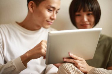 Genç Asyalı çift tablet bilgisayar kullanıyor.