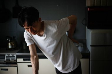 Sırtında acı hisseden Asyalı bir adam.