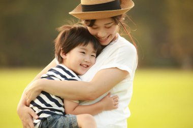 Mutlu anne ve oğul çimenlerde oynuyorlar.