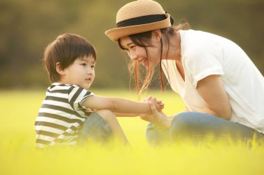 Mutlu anne ve oğul çimenlerde oynuyorlar.
