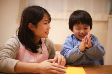 Küçük çocuk ve annesi mangırla oynuyorlar. 