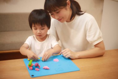 Anne ve oğlu çamurla oynuyor.