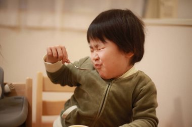 Küçük Asyalı çocuk mutfakta dondurma yiyor.