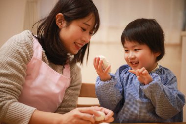 Küçük çocuk ve annesi mangırla oynuyorlar. 