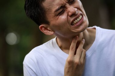 Boğazı ağrıyan Asyalı bir adamın yakın çekimi. 