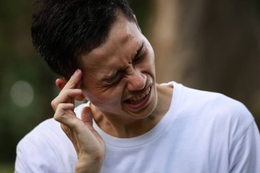 Baş ağrısı olan Asyalı genç bir adam. 