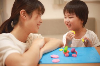 Anne ve oğlu çamurla oynuyor.