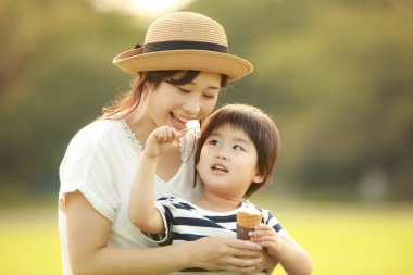 Anne, küçük oğlu için parkta dondurma besler.
