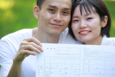 Elinde kağıt belge tutan genç bir çift.