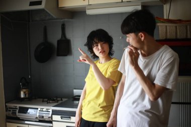 Genç Asyalı kadın mutsuzken erkek arkadaşı evde sigara yakıyor.